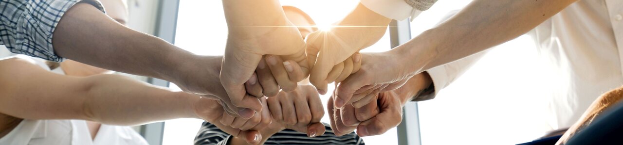 Als kollegiale Geste strecken mehrere Personen die Fäuste zusammen